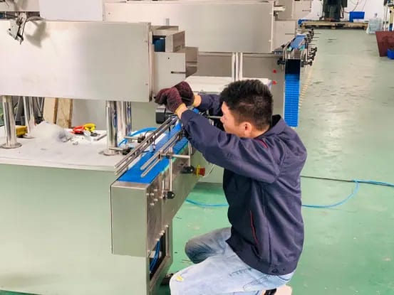 Technician fitting components near a conveyor on a packaging machine